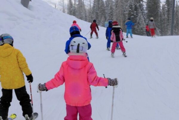 Young skiers in a lesson on a gentle slope, all wearing helmets