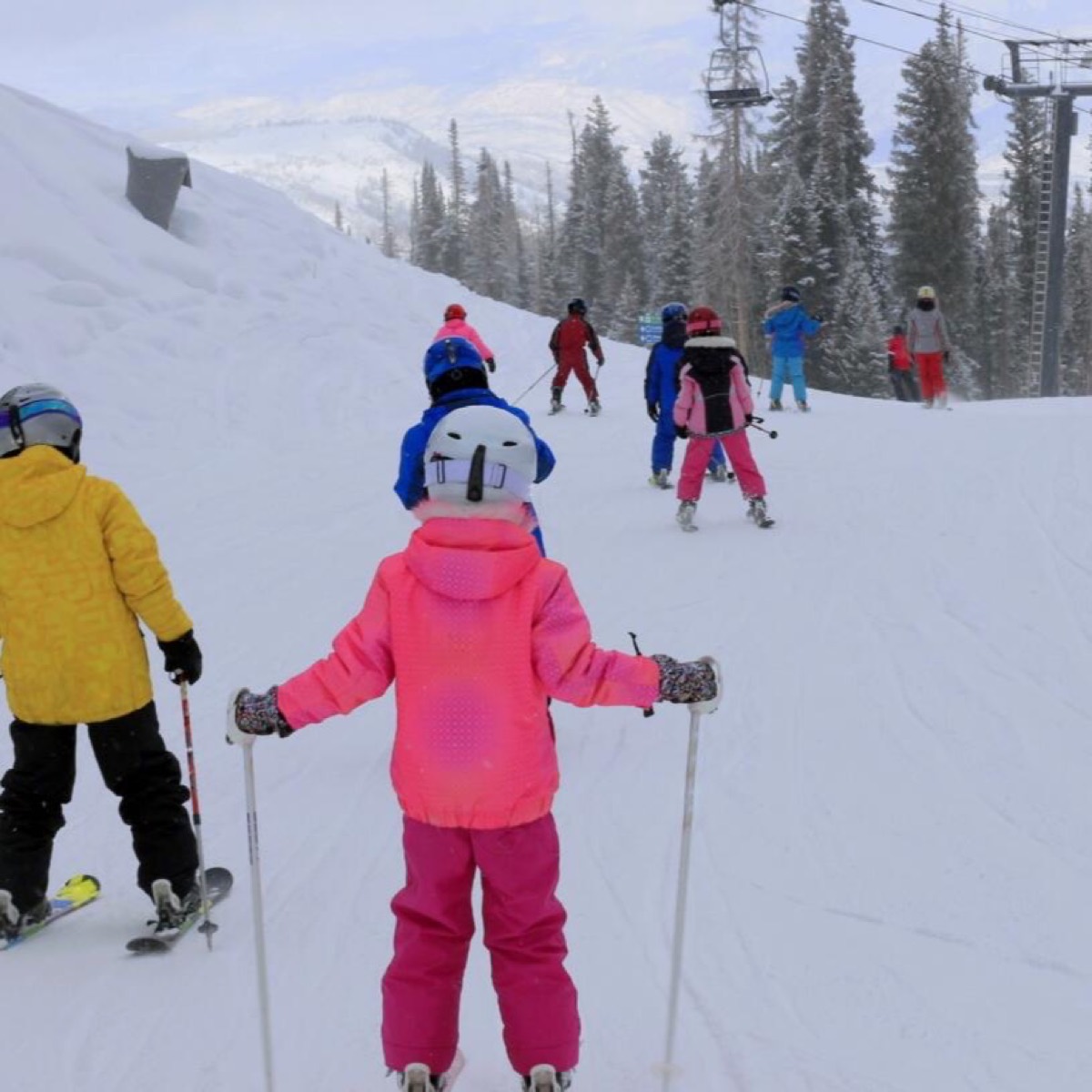 Young skiers in a lesson on a gentle slope, all wearing helmets