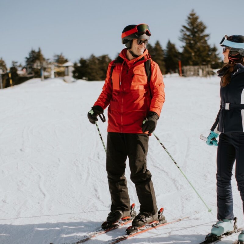 Ski coach and guest talking on a groomed run, both wearing helmets